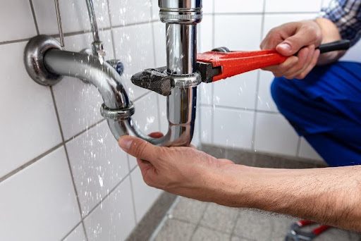 A professional plumber uses a wrench to resolve the issue of a leaky pipe in Caseyville, IL.